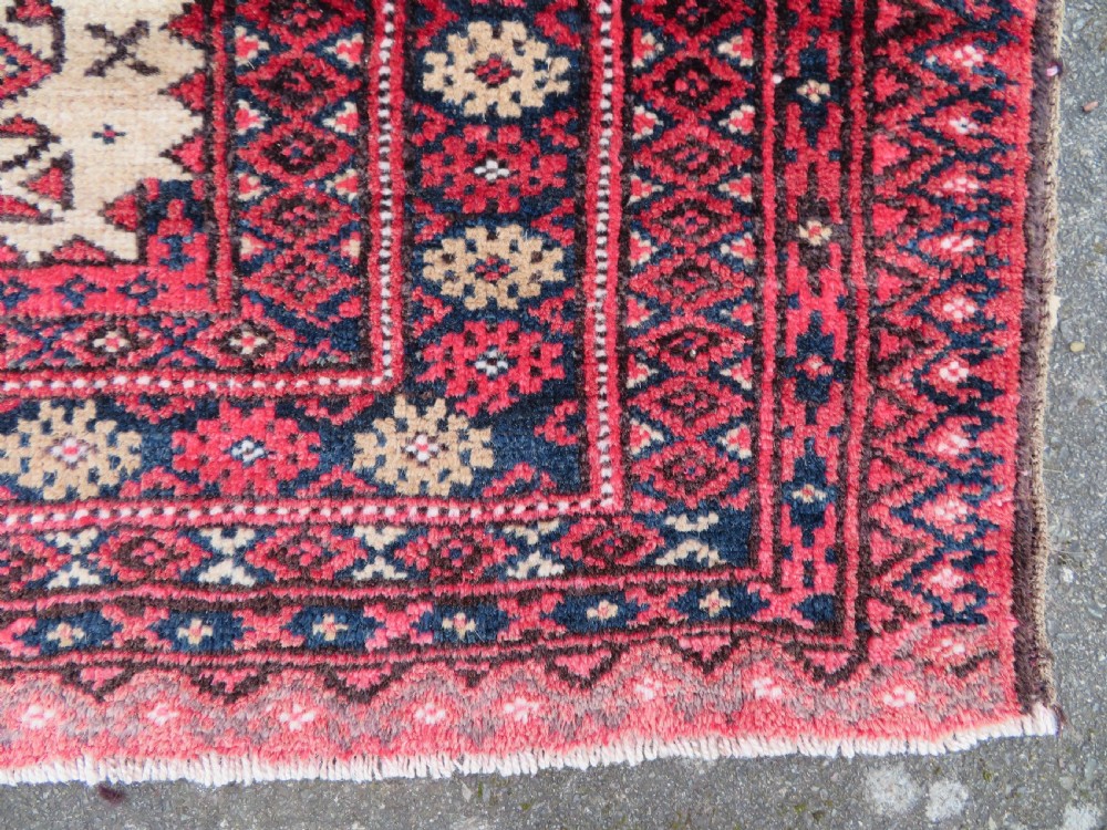 An antique hand-knotted Baluch wool rug featuring a central tree of life design on a cream field surrounded by red and navy geometric borders. View XI