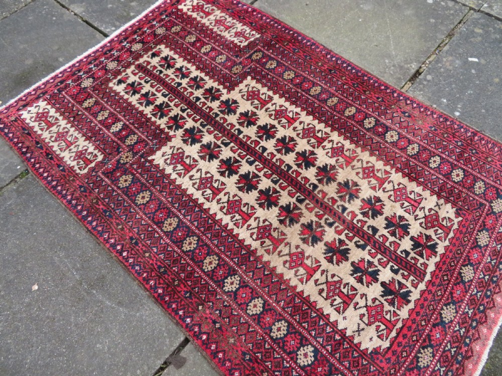An antique hand-knotted Baluch wool rug featuring a central tree of life design on a cream field surrounded by red and navy geometric borders. View XVII