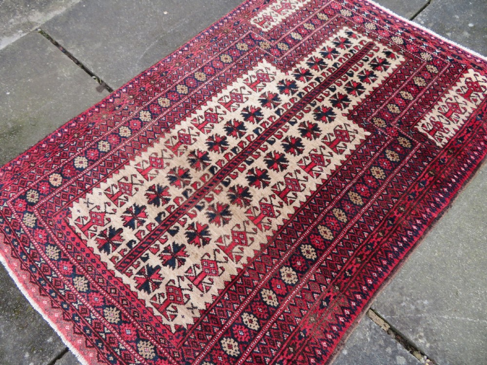 An antique hand-knotted Baluch wool rug featuring a central tree of life design on a cream field surrounded by red and navy geometric borders. View XVIII
