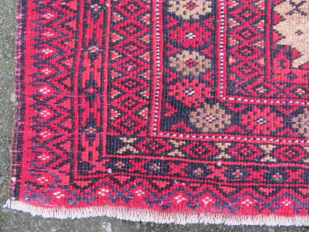 An antique hand-knotted Baluch wool rug featuring a central tree of life design on a cream field surrounded by red and navy geometric borders. View XX