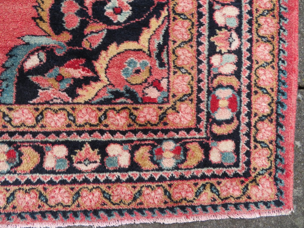 An antique Jozan Persian rug featuring a central floral medallion on a rose red field surrounded by intricate spandrels and multi-band patterned borders. View VII