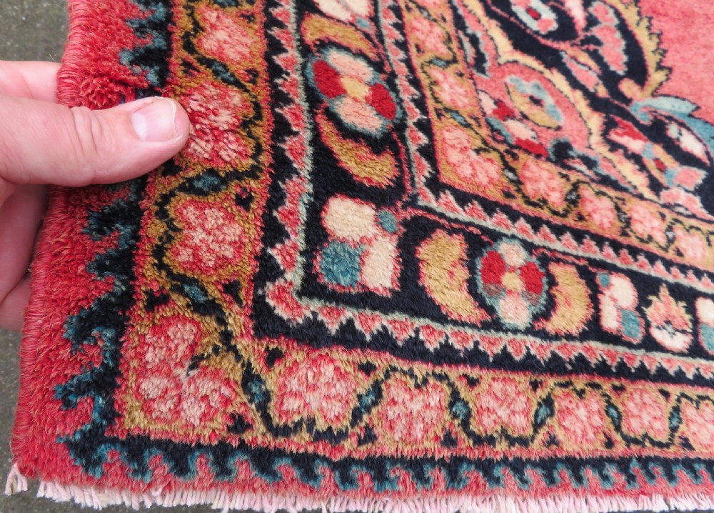 An antique Jozan Persian rug featuring a central floral medallion on a rose red field surrounded by intricate spandrels and multi-band patterned borders. View IX