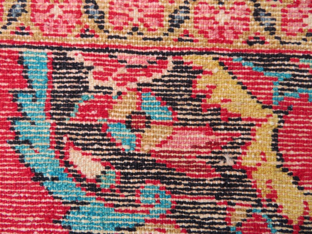 An antique Jozan Persian rug featuring a central floral medallion on a rose red field surrounded by intricate spandrels and multi-band patterned borders. View XVIII