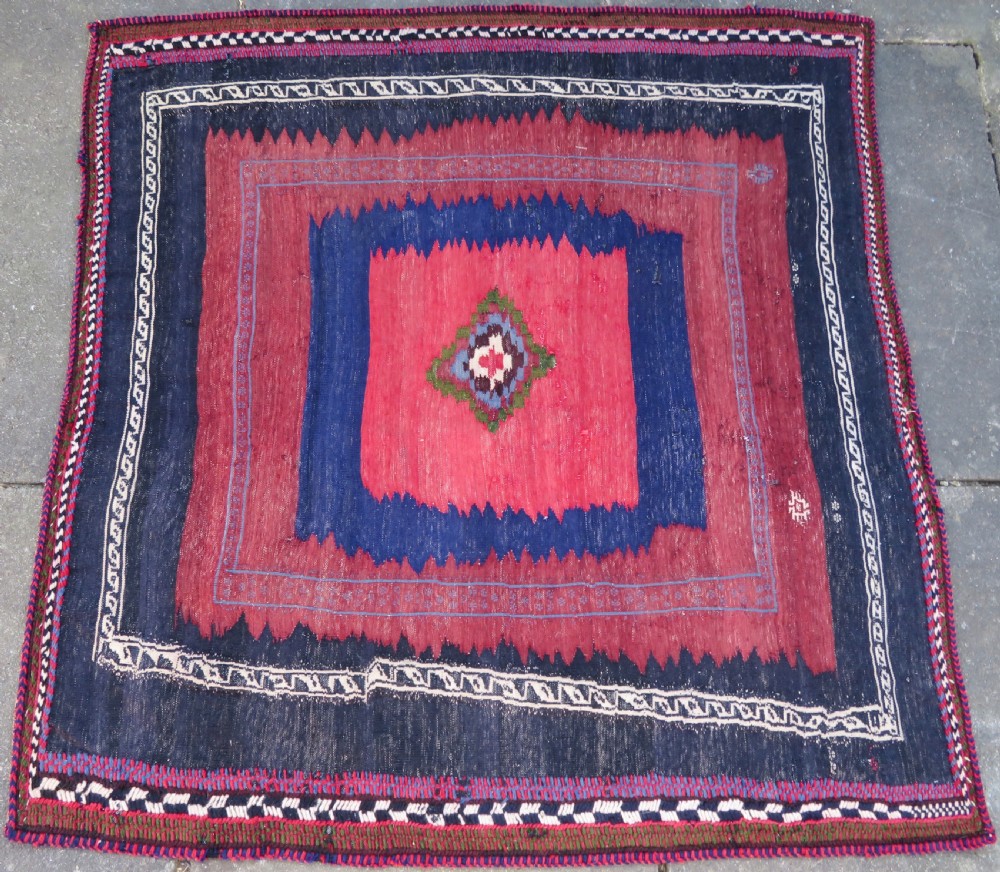 Square flatwoven antique Afshar sofreh rug featuring a central pink diamond medallion framed by nested red and navy blue stepped geometric borders. View III