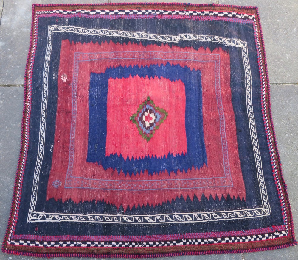 Square flatwoven antique Afshar sofreh rug featuring a central pink diamond medallion framed by nested red and navy blue stepped geometric borders. View IV