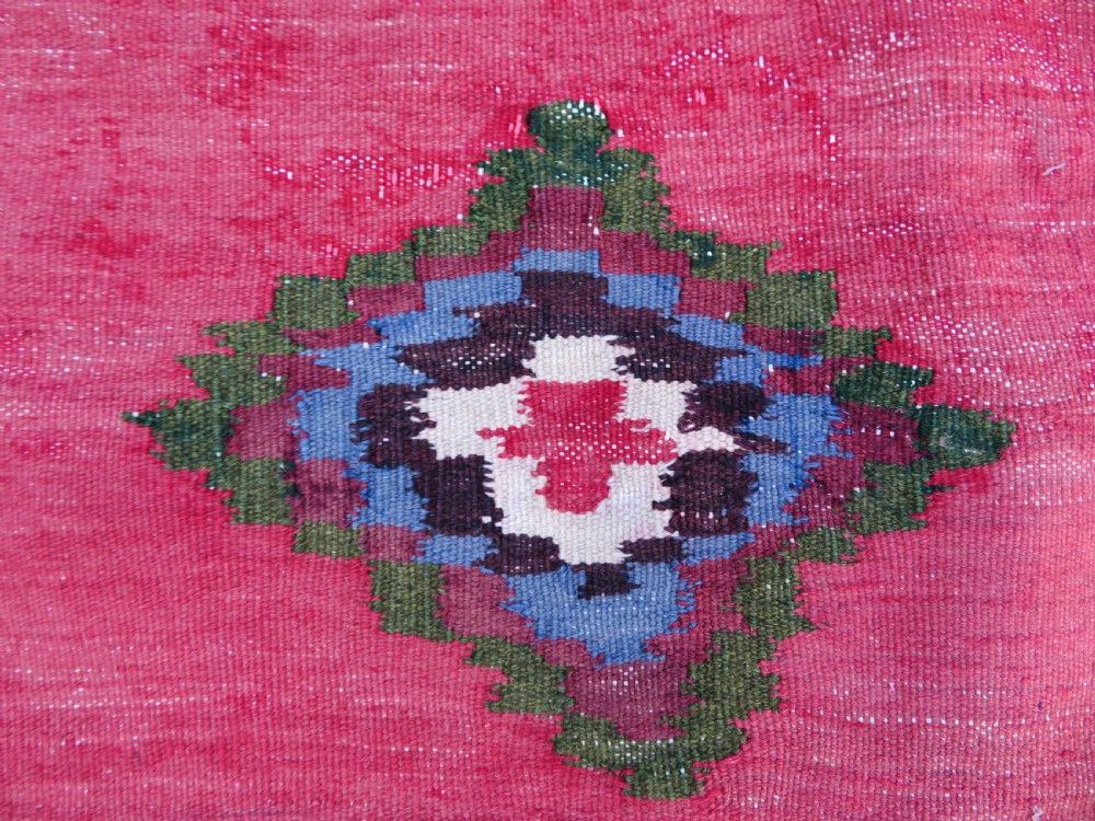 Square flatwoven antique Afshar sofreh rug featuring a central pink diamond medallion framed by nested red and navy blue stepped geometric borders. View V
