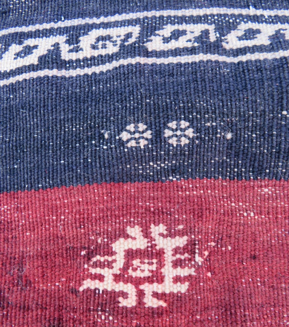Square flatwoven antique Afshar sofreh rug featuring a central pink diamond medallion framed by nested red and navy blue stepped geometric borders. View VI