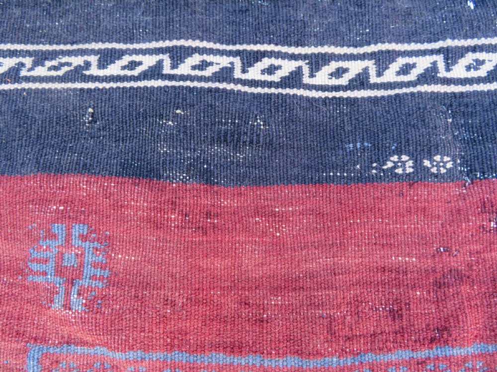 Square flatwoven antique Afshar sofreh rug featuring a central pink diamond medallion framed by nested red and navy blue stepped geometric borders. View VII