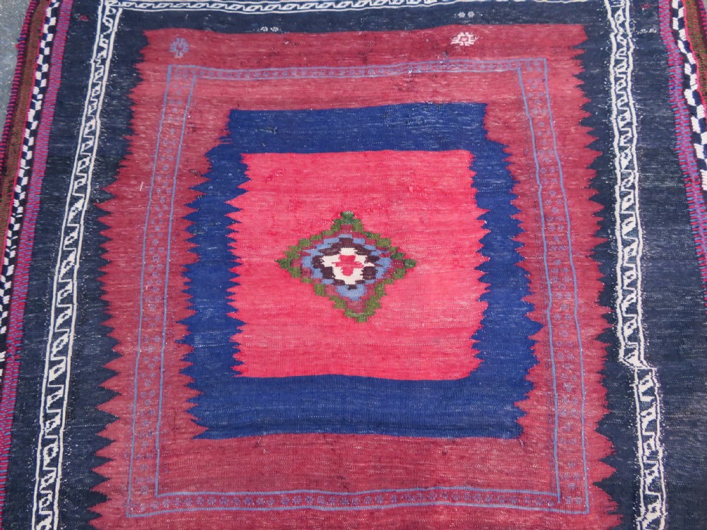 Square flatwoven antique Afshar sofreh rug featuring a central pink diamond medallion framed by nested red and navy blue stepped geometric borders. View XVIII