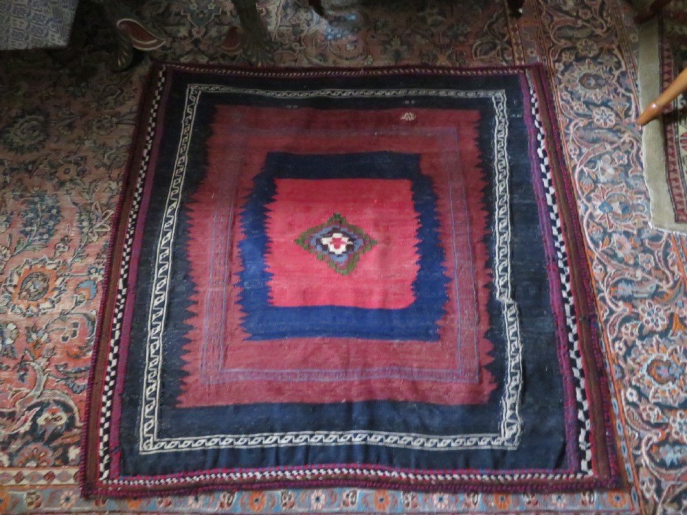 Square flatwoven antique Afshar sofreh rug featuring a central pink diamond medallion framed by nested red and navy blue stepped geometric borders. View XXVI