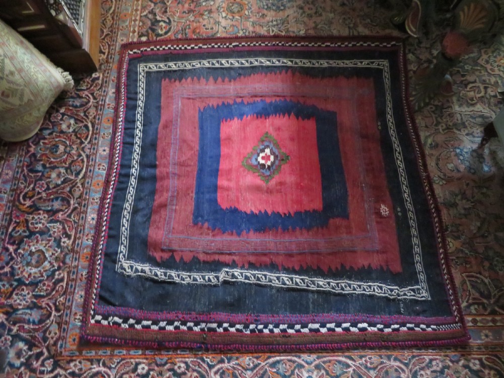 Square flatwoven antique Afshar sofreh rug featuring a central pink diamond medallion framed by nested red and navy blue stepped geometric borders. View XXVII