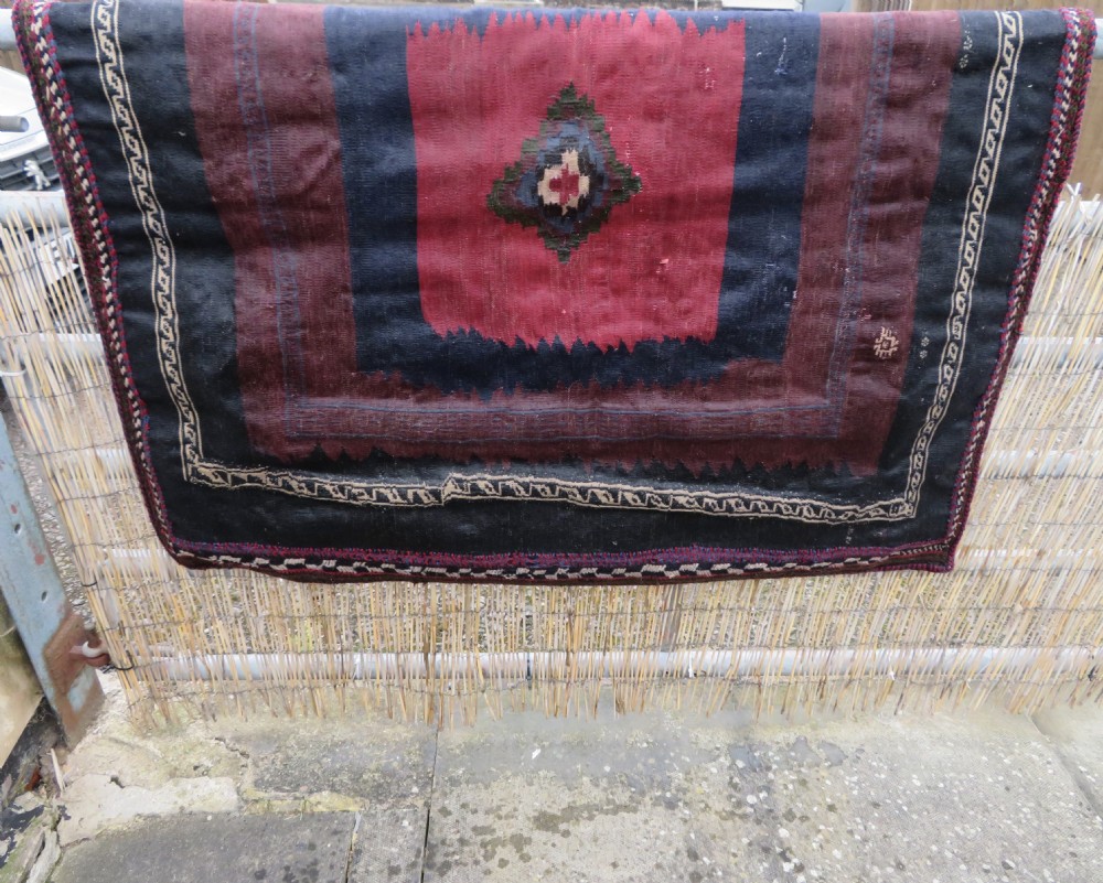 Square flatwoven antique Afshar sofreh rug featuring a central pink diamond medallion framed by nested red and navy blue stepped geometric borders. View XXXI