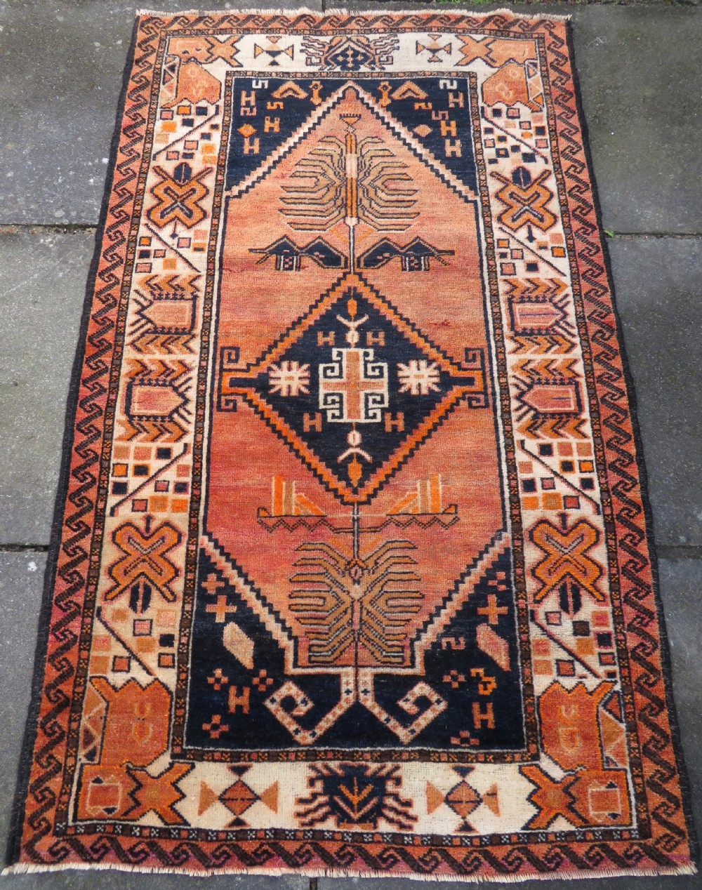 An antique hand-knotted Turkish Kurdish wool rug featuring a central terracotta diamond medallion surrounded by geometric motifs in dark indigo, cream, and orange shades. View II