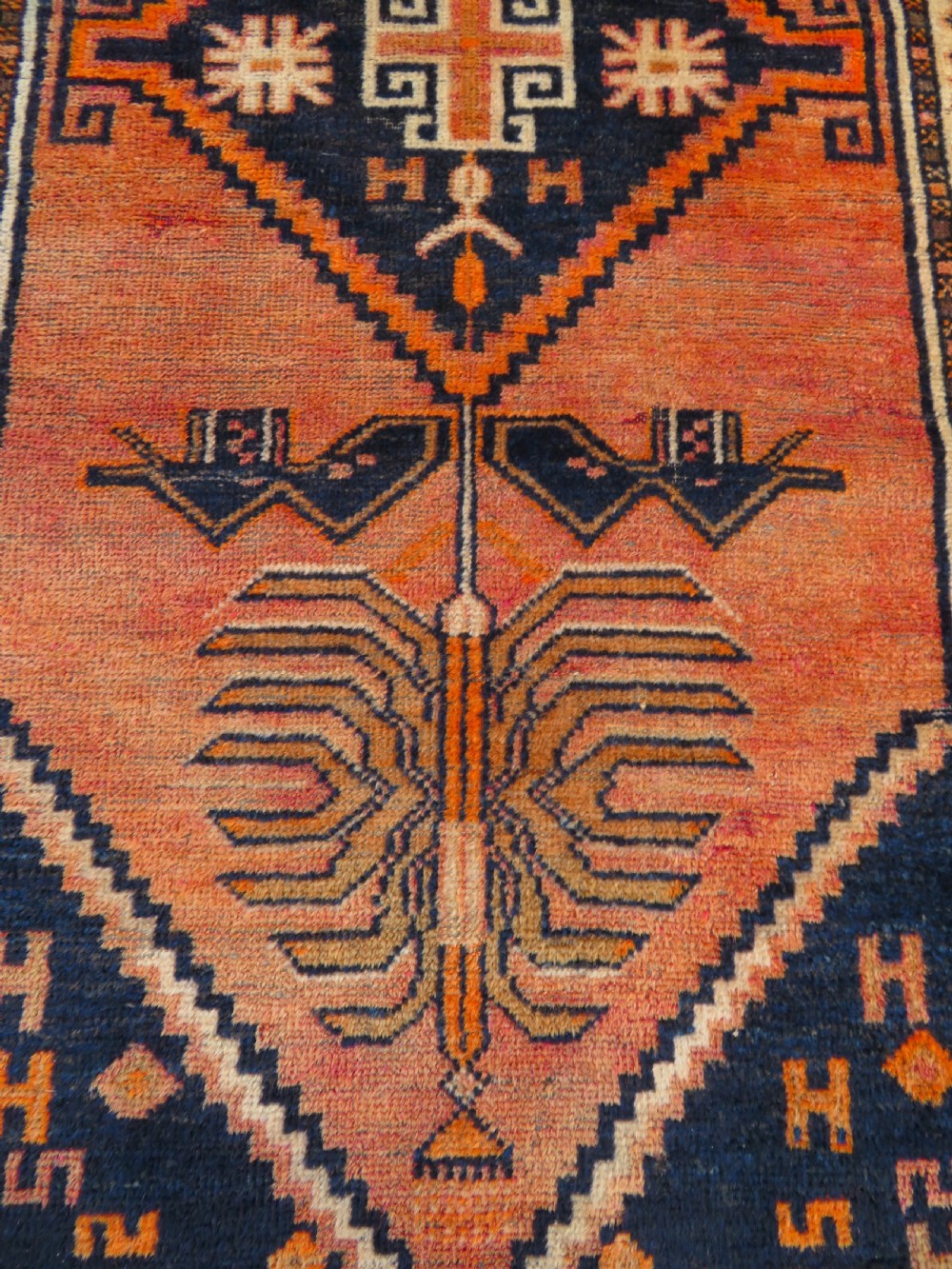 An antique hand-knotted Turkish Kurdish wool rug featuring a central terracotta diamond medallion surrounded by geometric motifs in dark indigo, cream, and orange shades. View VII