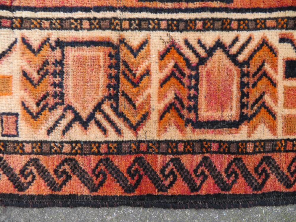 An antique hand-knotted Turkish Kurdish wool rug featuring a central terracotta diamond medallion surrounded by geometric motifs in dark indigo, cream, and orange shades. View IX