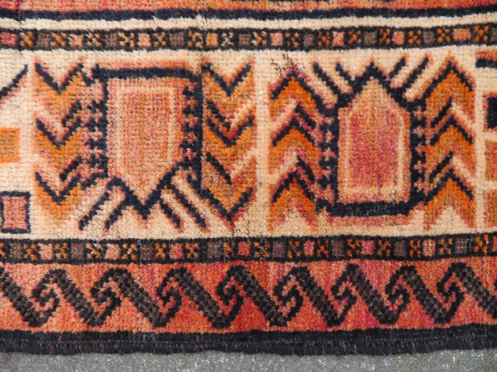 An antique hand-knotted Turkish Kurdish wool rug featuring a central terracotta diamond medallion surrounded by geometric motifs in dark indigo, cream, and orange shades. View X