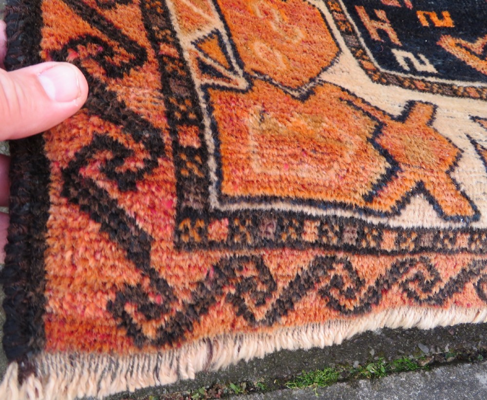 An antique hand-knotted Turkish Kurdish wool rug featuring a central terracotta diamond medallion surrounded by geometric motifs in dark indigo, cream, and orange shades. View XI