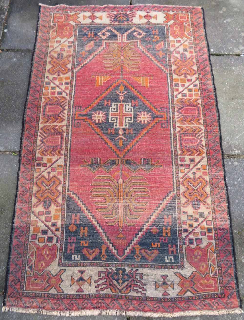 An antique hand-knotted Turkish Kurdish wool rug featuring a central terracotta diamond medallion surrounded by geometric motifs in dark indigo, cream, and orange shades. View XVIII