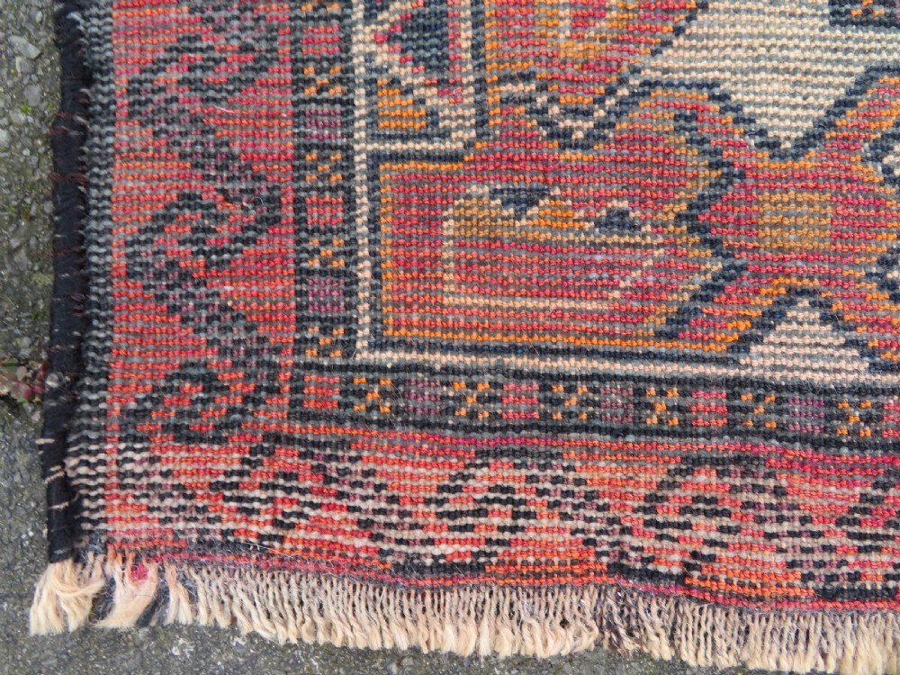 An antique hand-knotted Turkish Kurdish wool rug featuring a central terracotta diamond medallion surrounded by geometric motifs in dark indigo, cream, and orange shades. View XIX