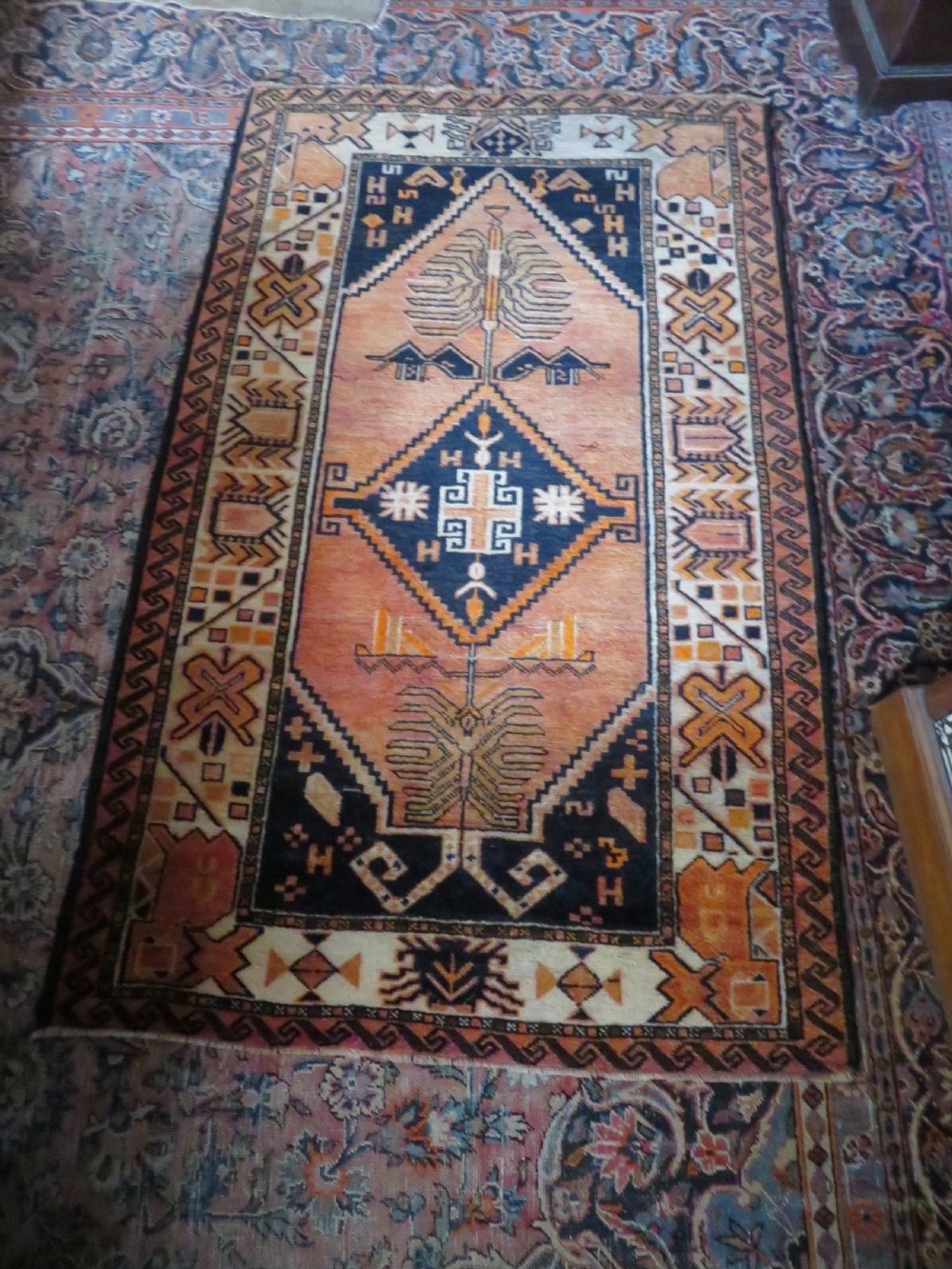 An antique hand-knotted Turkish Kurdish wool rug featuring a central terracotta diamond medallion surrounded by geometric motifs in dark indigo, cream, and orange shades. View XXII