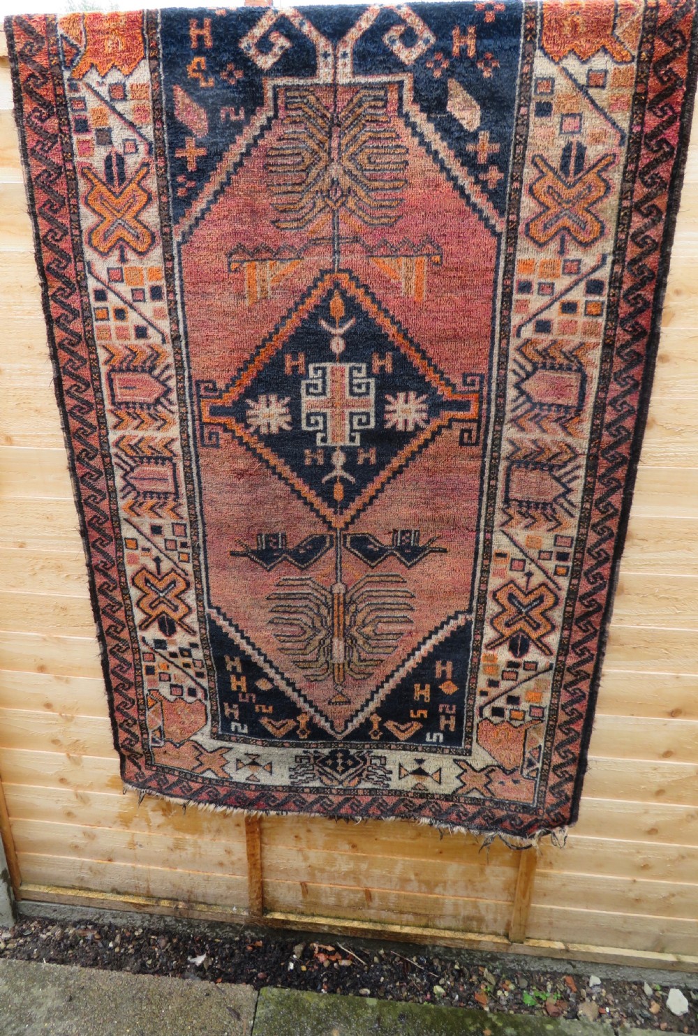 An antique hand-knotted Turkish Kurdish wool rug featuring a central terracotta diamond medallion surrounded by geometric motifs in dark indigo, cream, and orange shades. View XXV