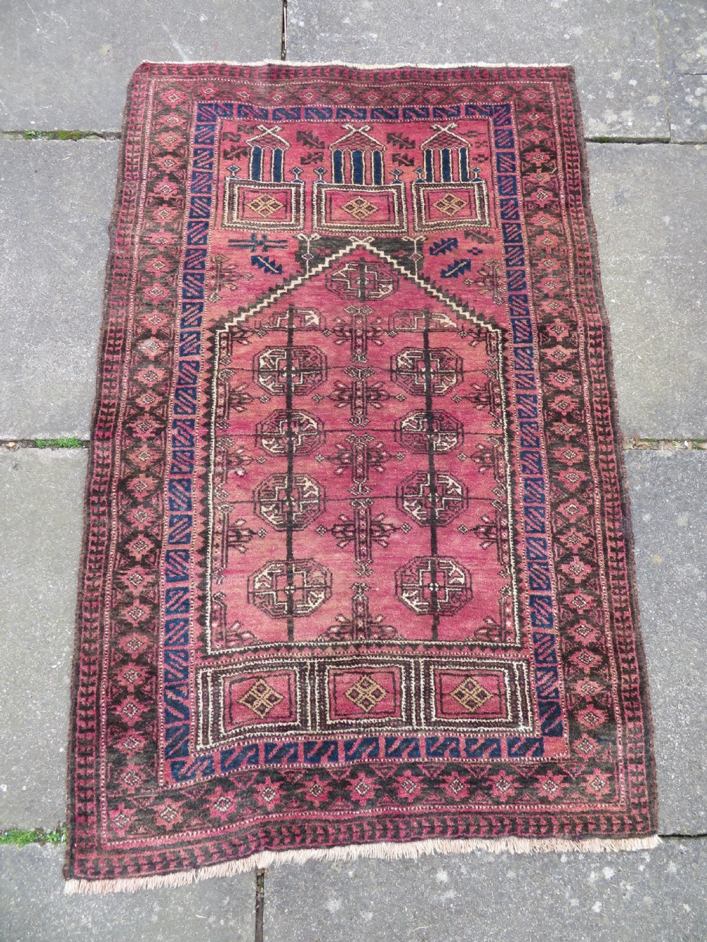 An antique hand-knotted Turkmen Kizil Ayak wool prayer rug featuring a triple mihrab arch design in deep red, dark blue, and charcoal shades.