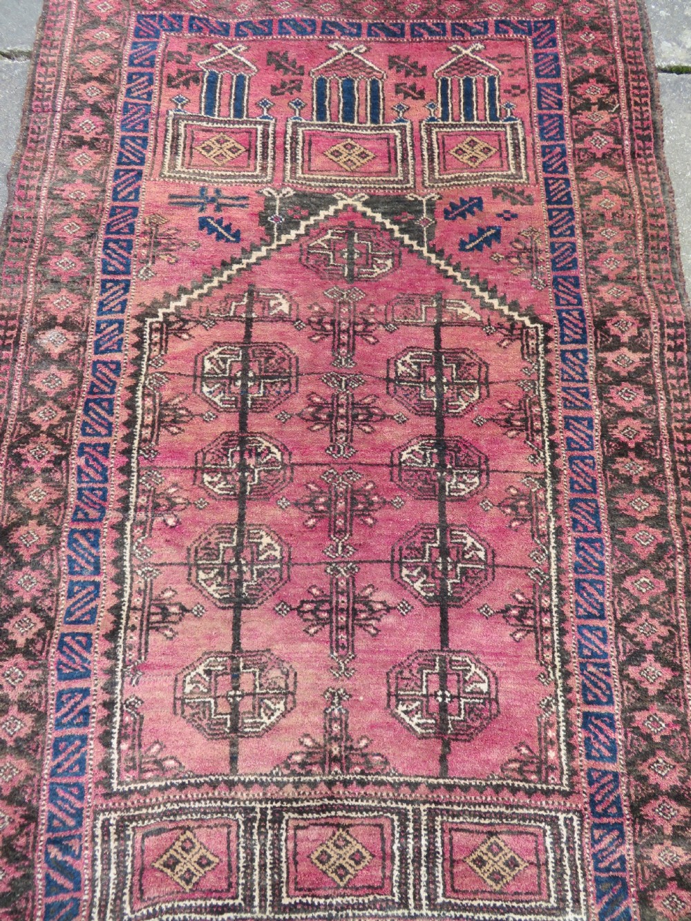 An antique hand-knotted Turkmen Kizil Ayak wool prayer rug featuring a triple mihrab arch design in deep red, dark blue, and charcoal shades. View IV