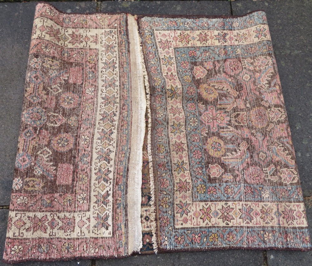 An antique Kurdish wool runner rug featuring a dark brown central field filled with pink and blue geometric motifs surrounded by a cream floral border. View XXI
