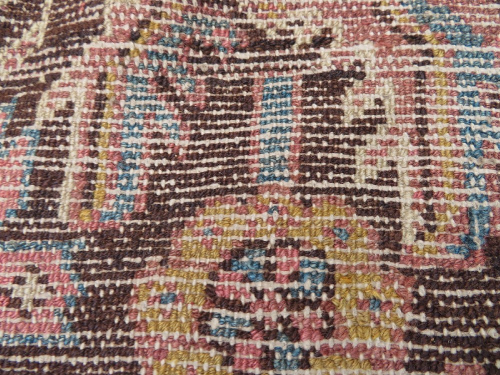 An antique Kurdish wool runner rug featuring a dark brown central field filled with pink and blue geometric motifs surrounded by a cream floral border. View XXIII