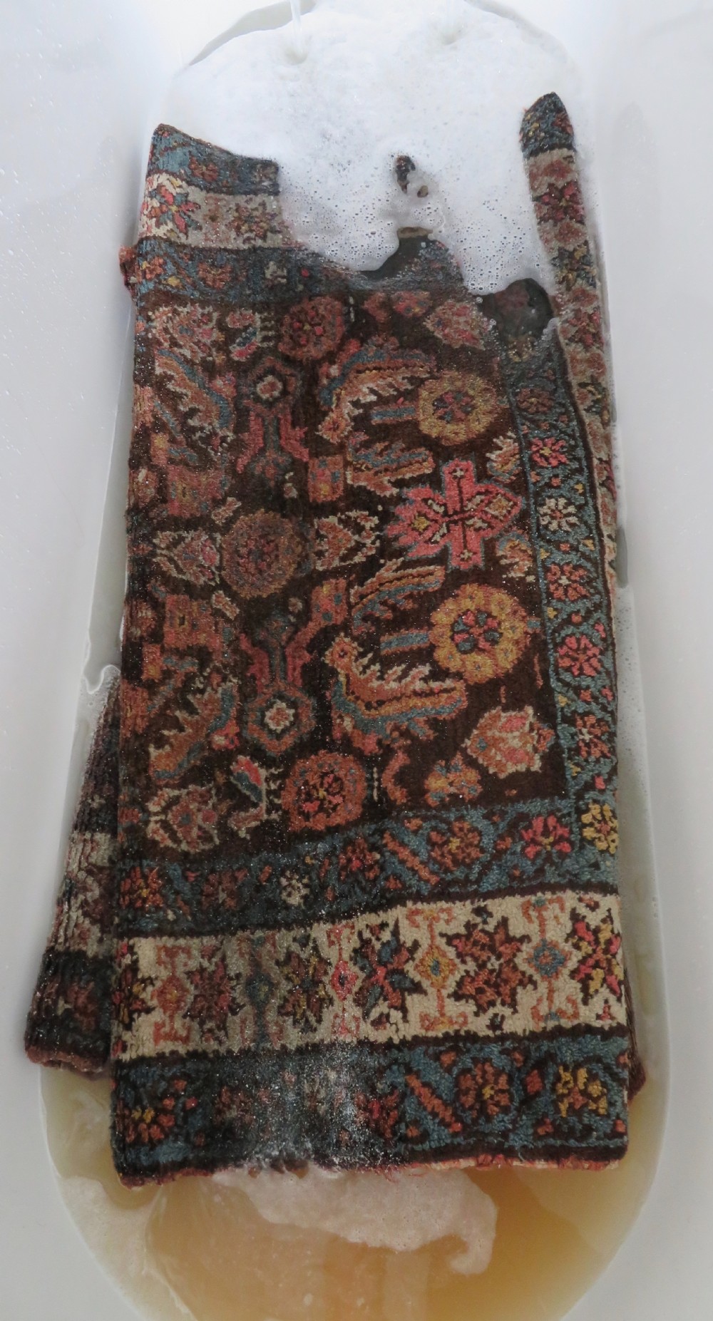 An antique Kurdish wool runner rug featuring a dark brown central field filled with pink and blue geometric motifs surrounded by a cream floral border. View XXIX