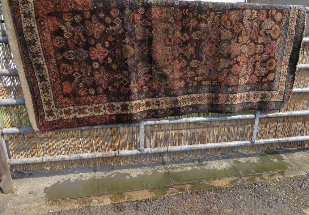 An antique Kurdish wool runner rug featuring a dark brown central field filled with pink and blue geometric motifs surrounded by a cream floral border. View XXXI