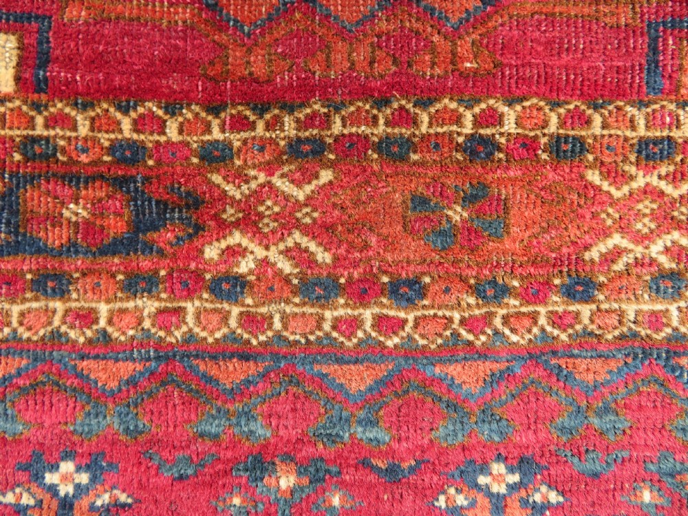 A mid-nineteenth-century hand-knotted Tekke Turkmen wool chuval face featuring six octagonal guls on a deep crimson ground with an intricate bottom elem border. View III