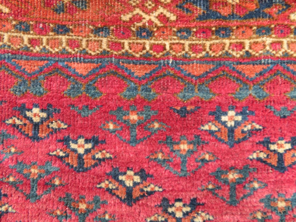 A mid-nineteenth-century hand-knotted Tekke Turkmen wool chuval face featuring six octagonal guls on a deep crimson ground with an intricate bottom elem border. View V
