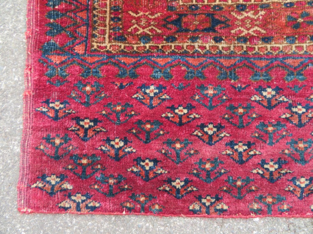A mid-nineteenth-century hand-knotted Tekke Turkmen wool chuval face featuring six octagonal guls on a deep crimson ground with an intricate bottom elem border. View VII