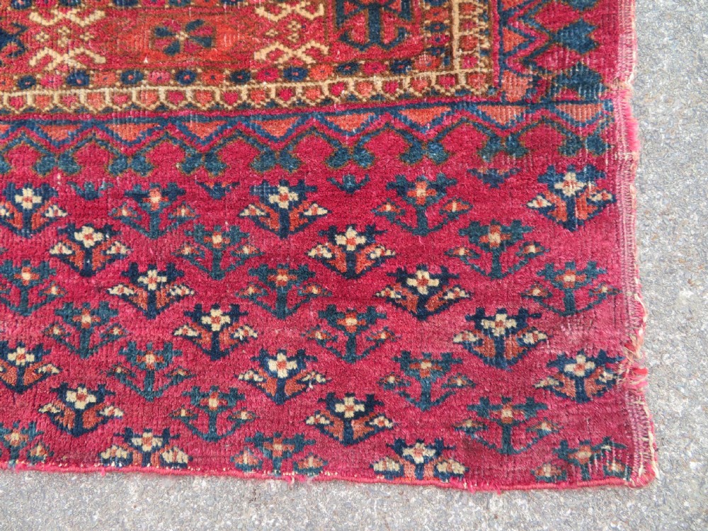 A mid-nineteenth-century hand-knotted Tekke Turkmen wool chuval face featuring six octagonal guls on a deep crimson ground with an intricate bottom elem border. View X