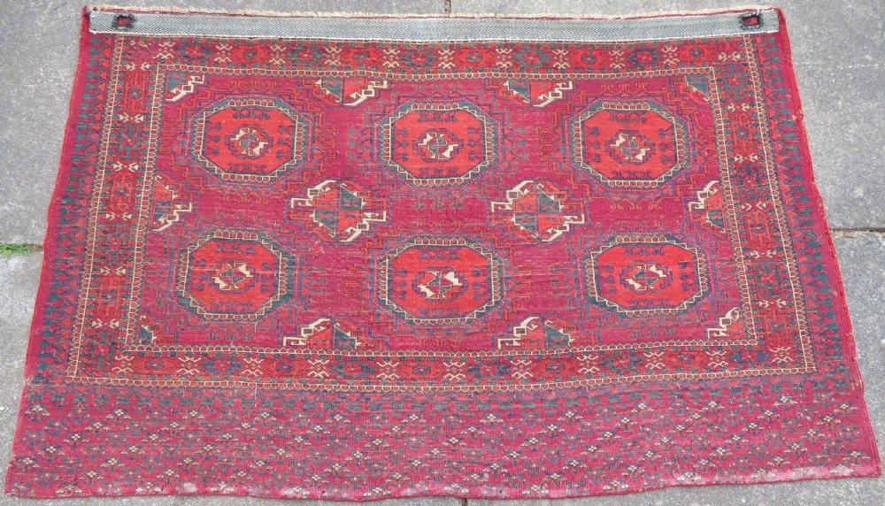 A mid-nineteenth-century hand-knotted Tekke Turkmen wool chuval face featuring six octagonal guls on a deep crimson ground with an intricate bottom elem border. View XV