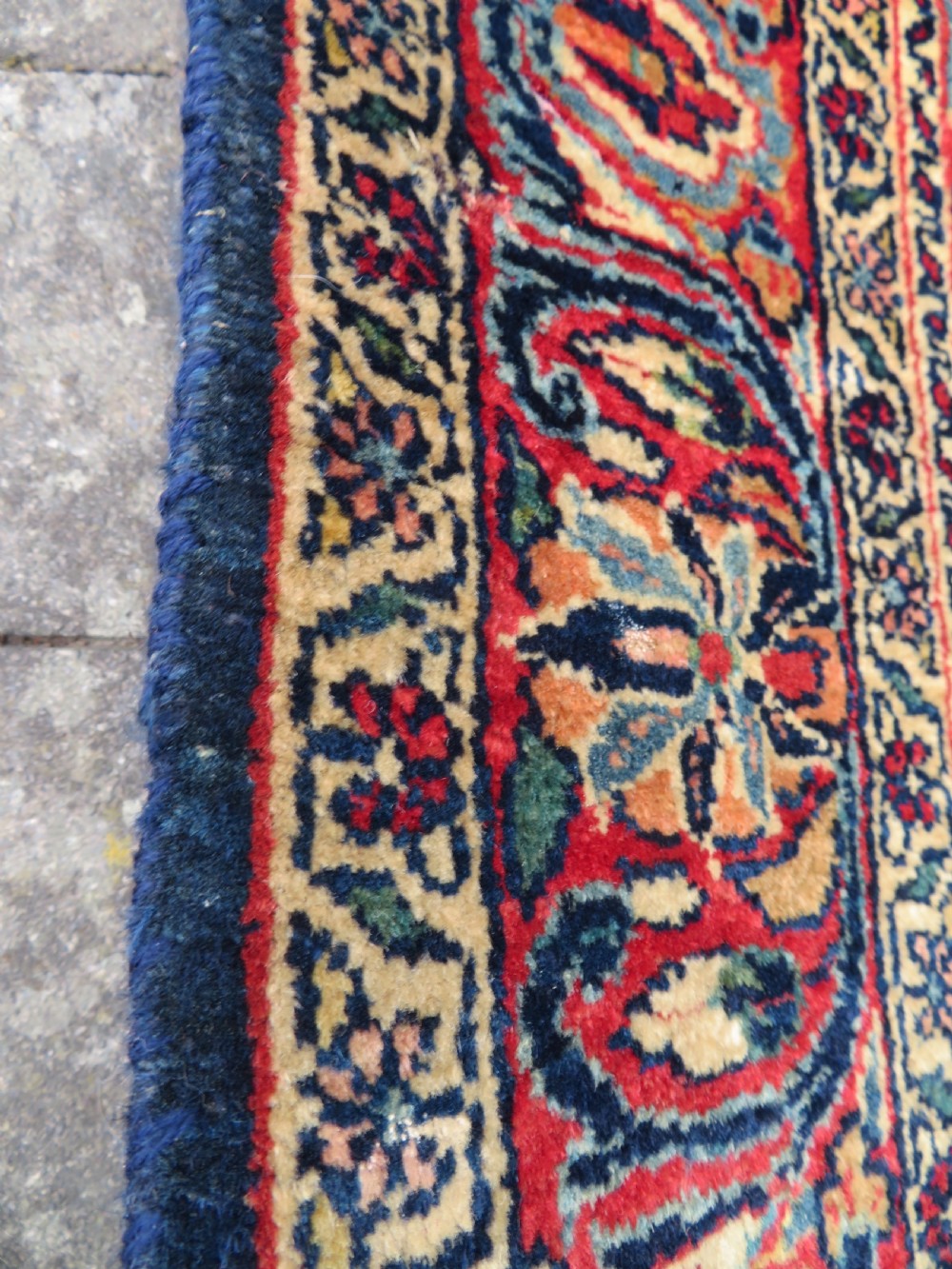 An antique West Persian Sarouk wool rug featuring a detailed central floral medallion framed by dense floral vine scrolls in shades of red, dark navy, cream, and blue. View XIX