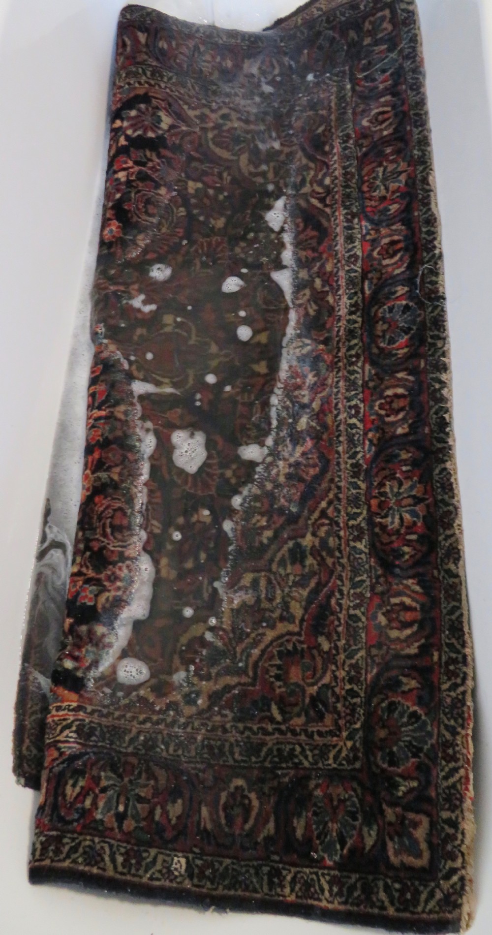 An antique West Persian Sarouk wool rug featuring a detailed central floral medallion framed by dense floral vine scrolls in shades of red, dark navy, cream, and blue. View XXVII
