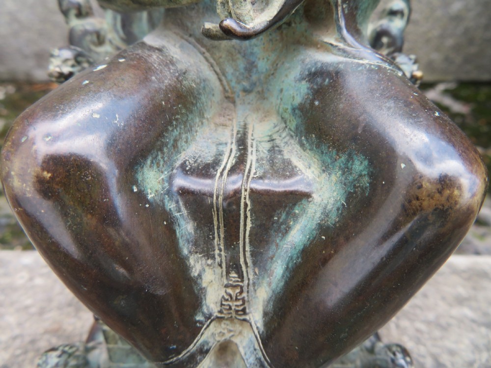 A dark copper alloy sculpture depicting Buddha seated on an ornate throne with legs lowered in the European posture. View VII