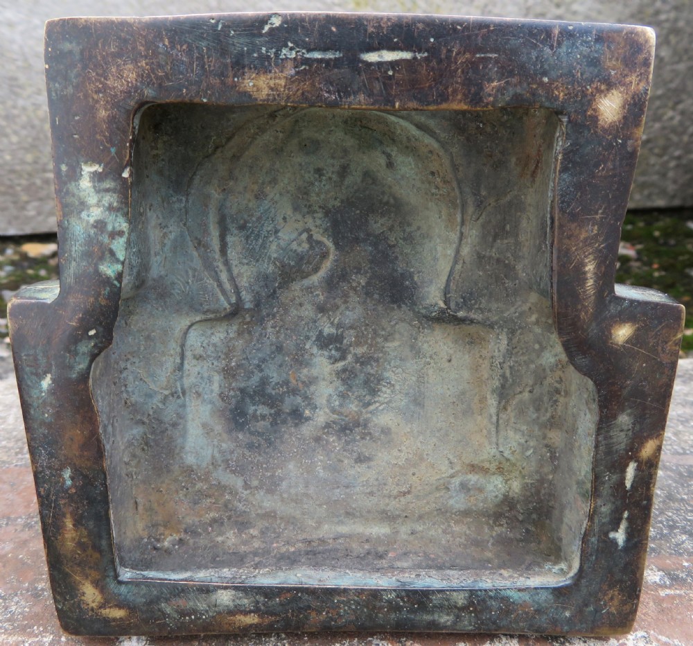 A dark copper alloy sculpture depicting Buddha seated on an ornate throne with legs lowered in the European posture. View XX