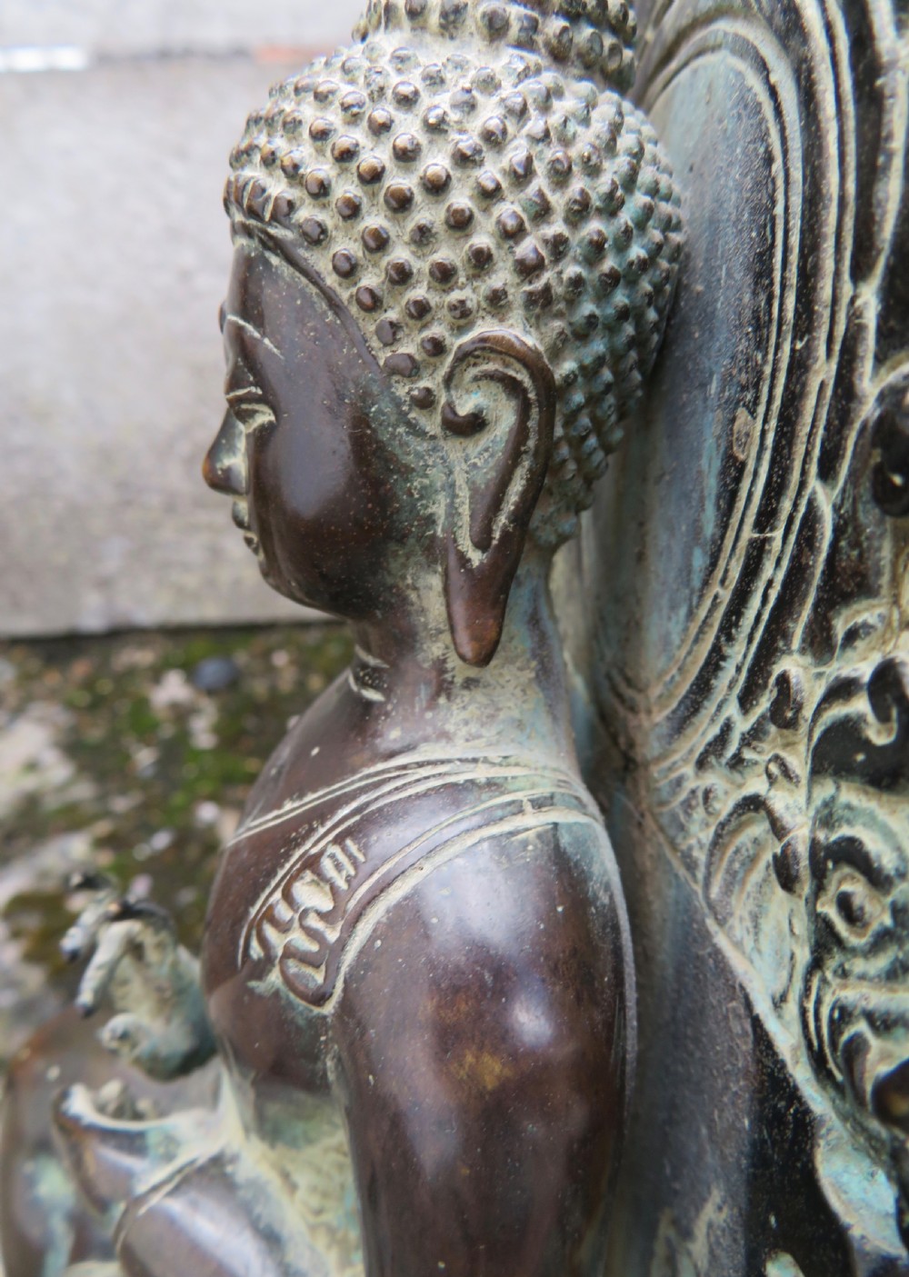 A dark copper alloy sculpture depicting Buddha seated on an ornate throne with legs lowered in the European posture. View XXV