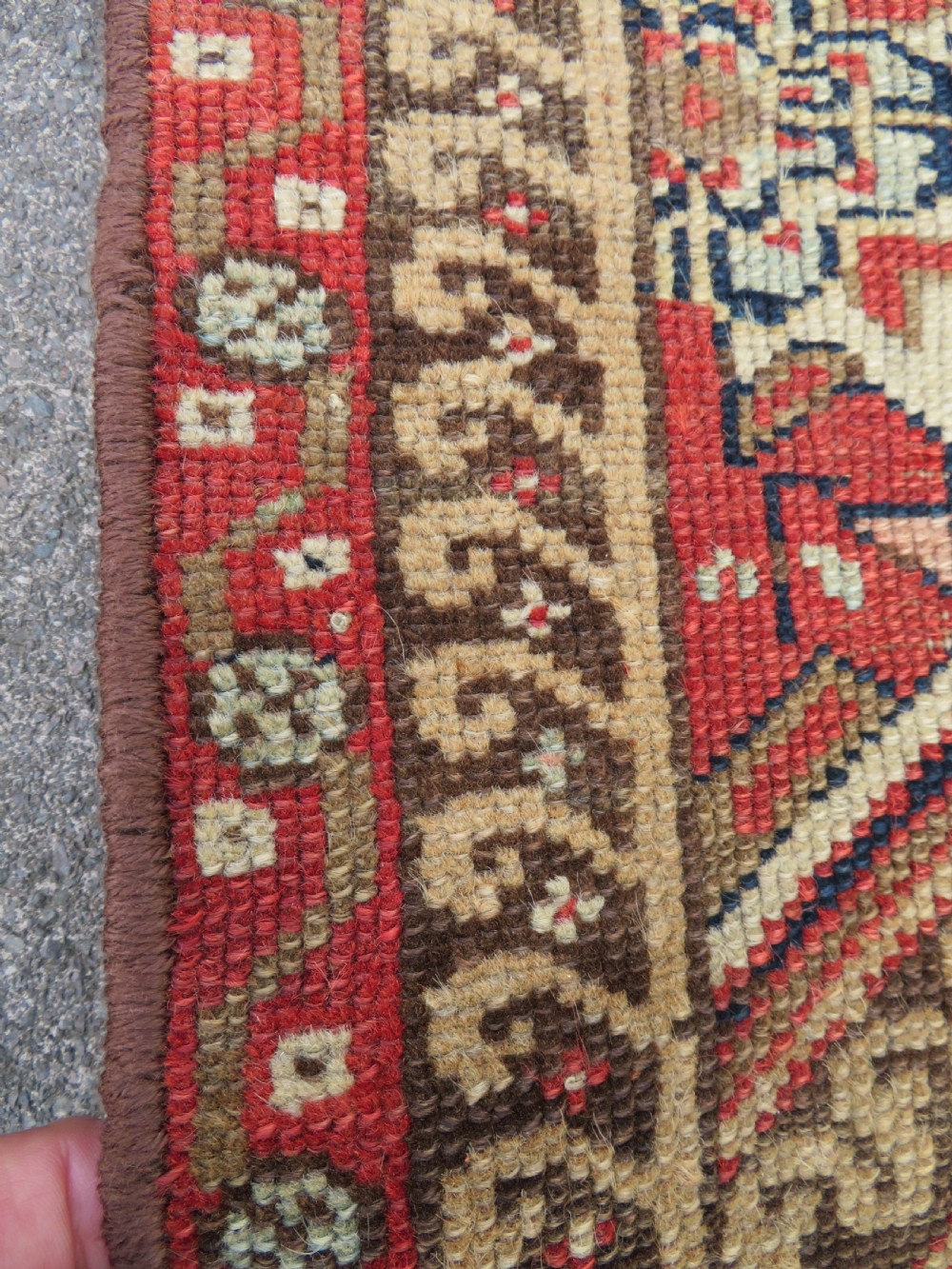 An antique North West Persian Kurdish hand-knotted wool narrow hallway runner featuring repeating diamond medallions in terracotta red, brown, and cream tones. View X