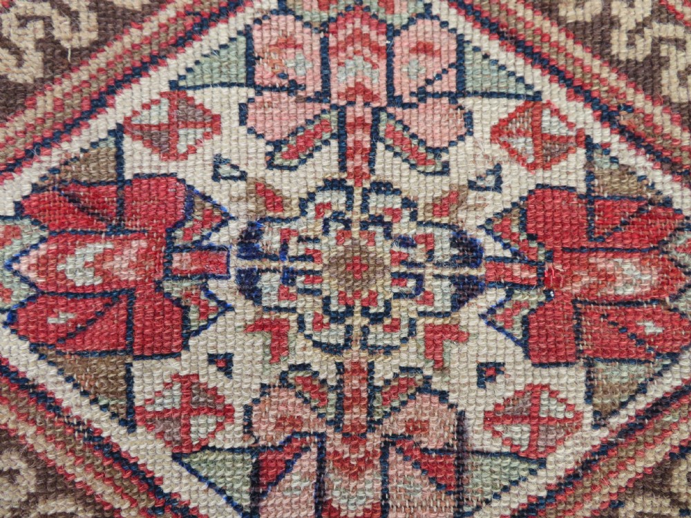 An antique North West Persian Kurdish hand-knotted wool narrow hallway runner featuring repeating diamond medallions in terracotta red, brown, and cream tones. View XI