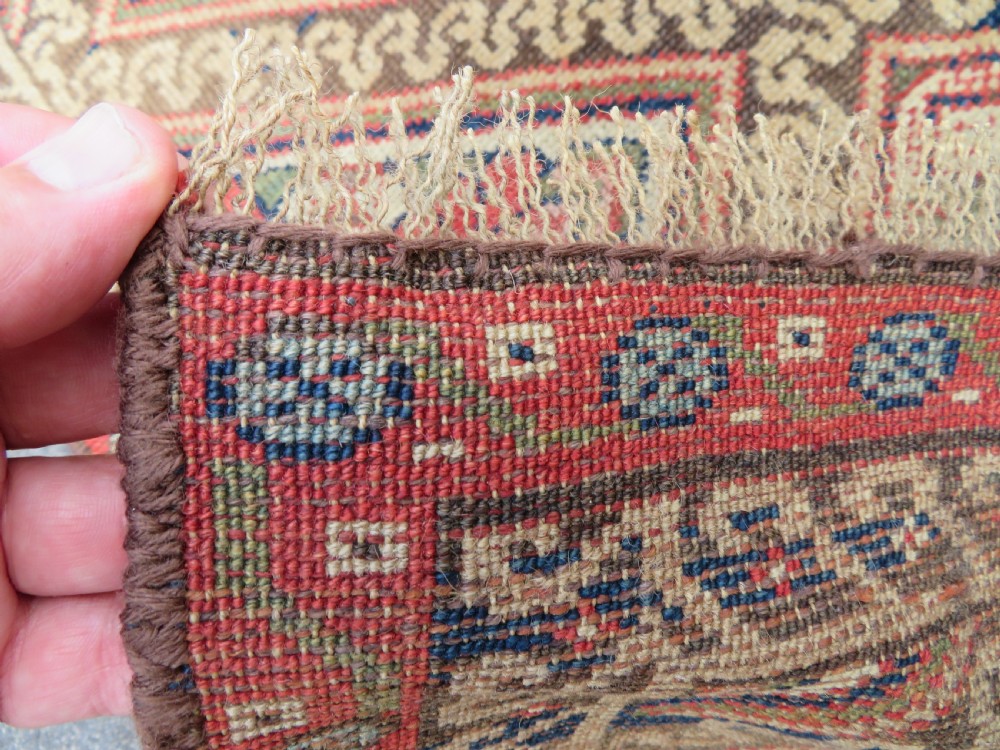 An antique North West Persian Kurdish hand-knotted wool narrow hallway runner featuring repeating diamond medallions in terracotta red, brown, and cream tones. View XIII