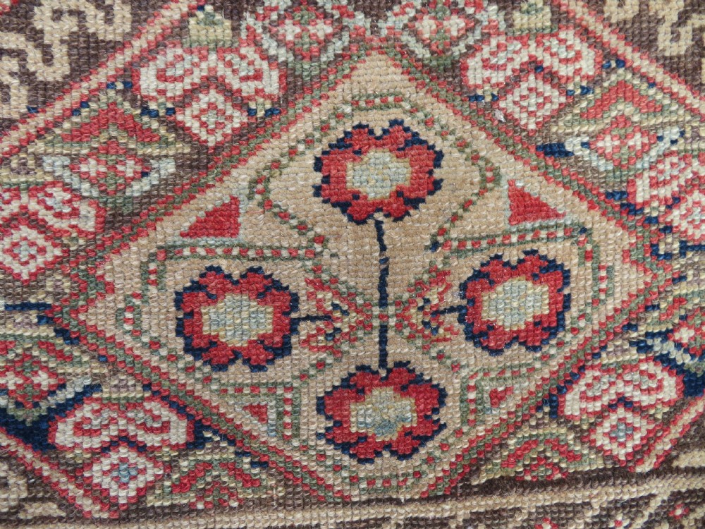 An antique North West Persian Kurdish hand-knotted wool narrow hallway runner featuring repeating diamond medallions in terracotta red, brown, and cream tones. View XIV