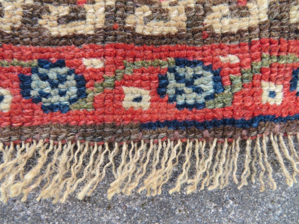 An antique North West Persian Kurdish hand-knotted wool narrow hallway runner featuring repeating diamond medallions in terracotta red, brown, and cream tones. View XV