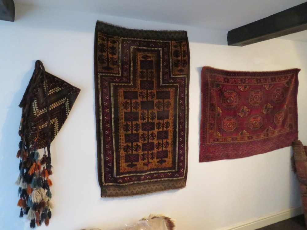 A hand-woven Yomut Turkmen Ok Bash tent-pole bag featuring geometric chevron patterns in rust brown, indigo, and cream wool, finished with braided ties and multi-coloured tassels. View V