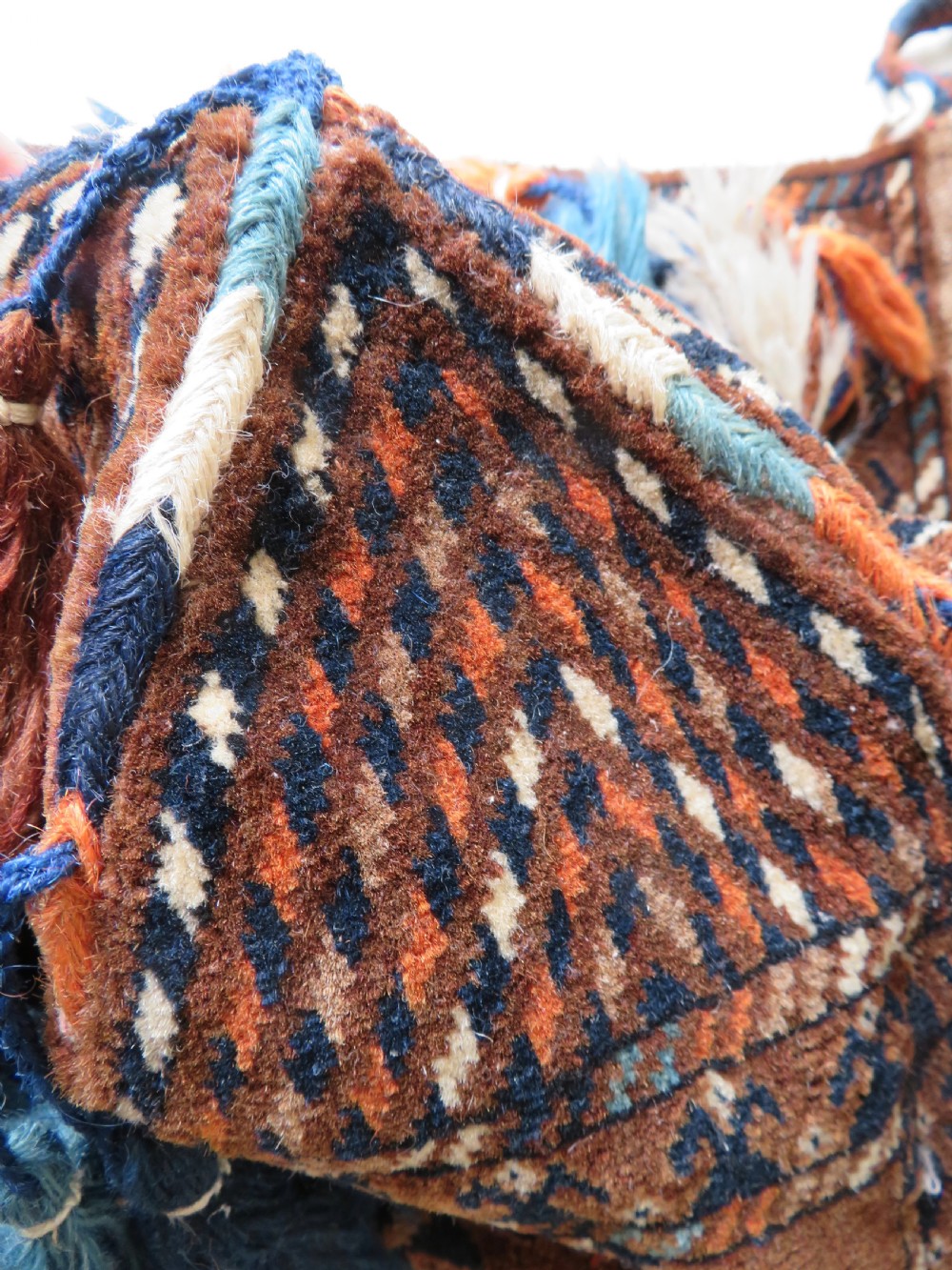 A hand-woven Yomut Turkmen Ok Bash tent-pole bag featuring geometric chevron patterns in rust brown, indigo, and cream wool, finished with braided ties and multi-coloured tassels. View XI