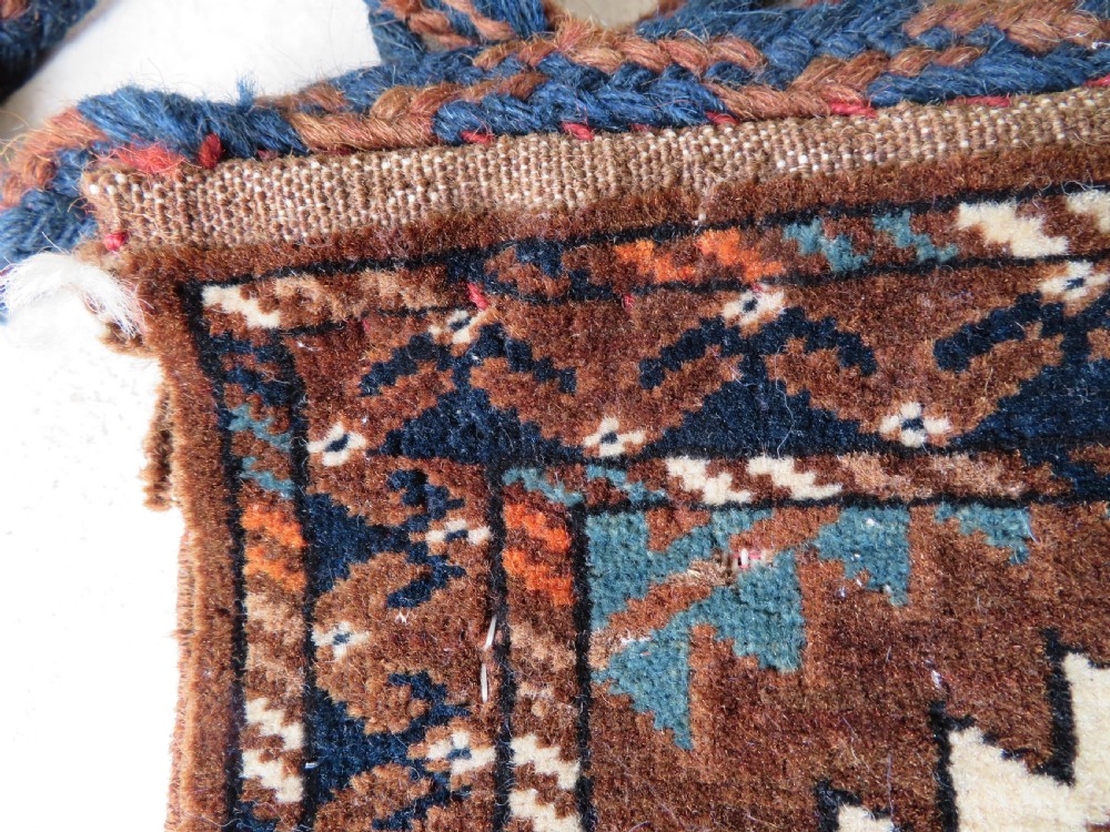 A hand-woven Yomut Turkmen Ok Bash tent-pole bag featuring geometric chevron patterns in rust brown, indigo, and cream wool, finished with braided ties and multi-coloured tassels. View XIII