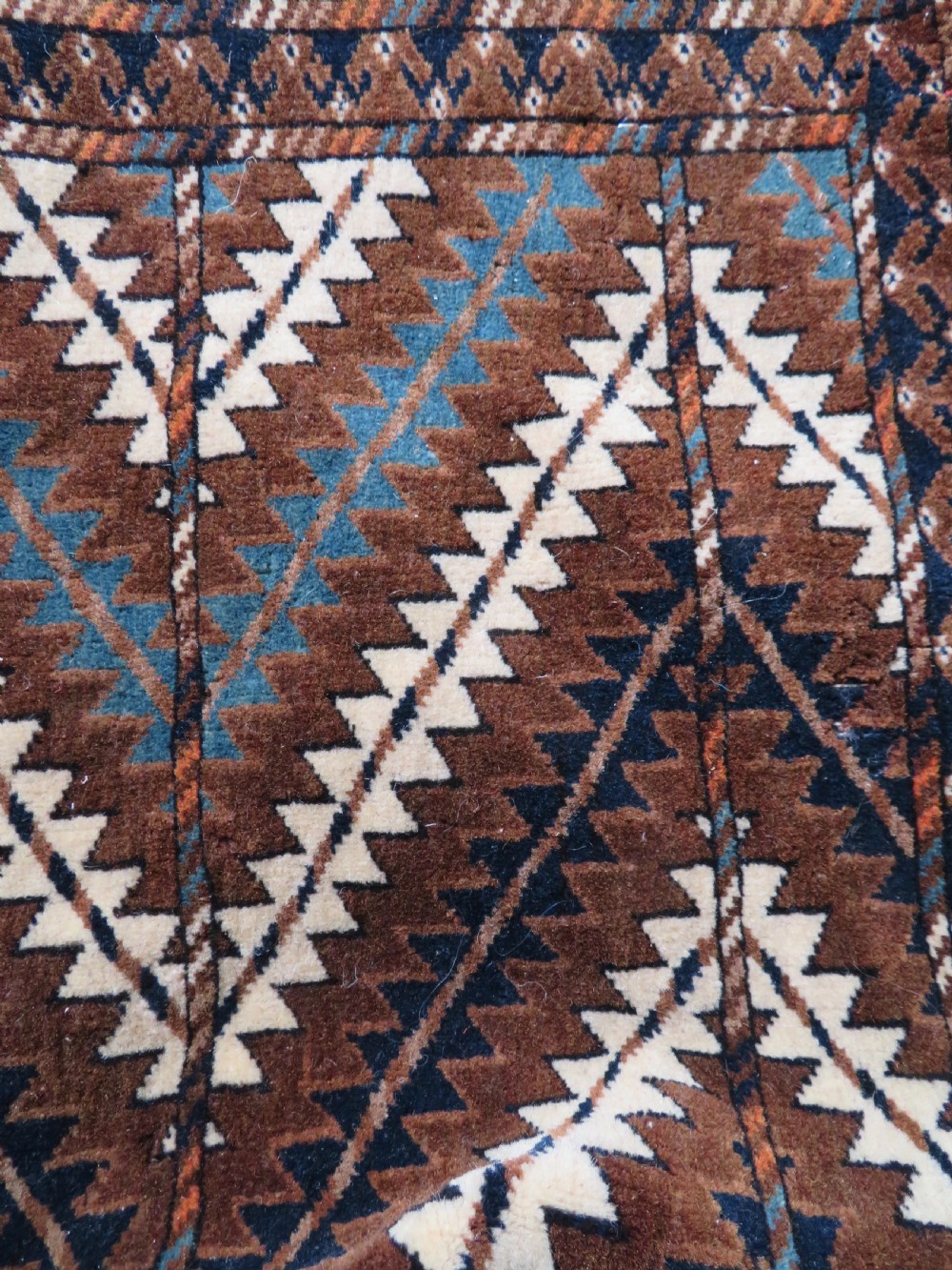 A hand-woven Yomut Turkmen Ok Bash tent-pole bag featuring geometric chevron patterns in rust brown, indigo, and cream wool, finished with braided ties and multi-coloured tassels. View XIV